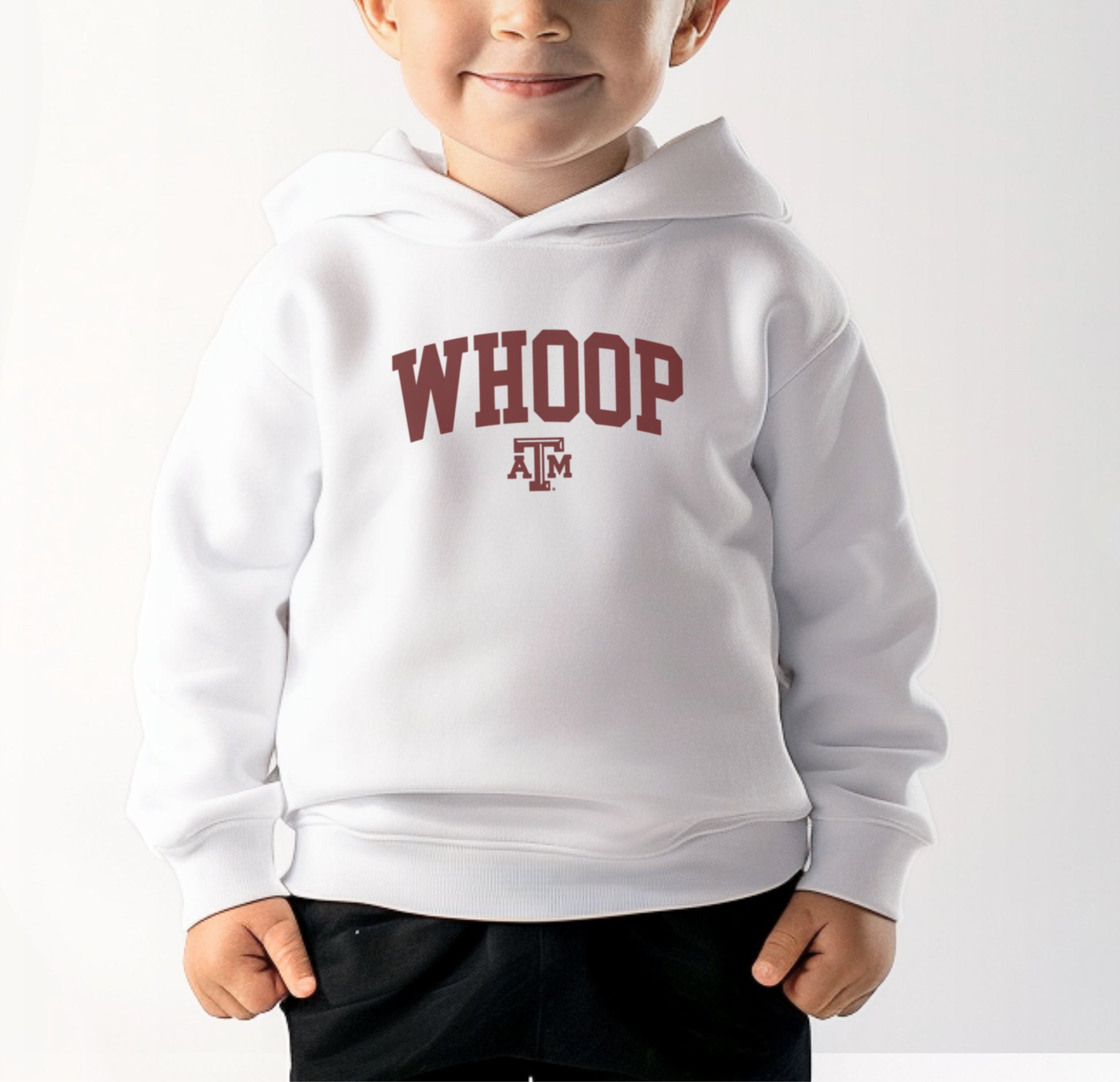 A model wears the White Toddler Unisex Texas A&M Whoop Collegiate Hooded Sweatshirt.  The ﻿Texas A&M Whoop Collegiate﻿ graphic is in bold Maroon in a Varsity style.