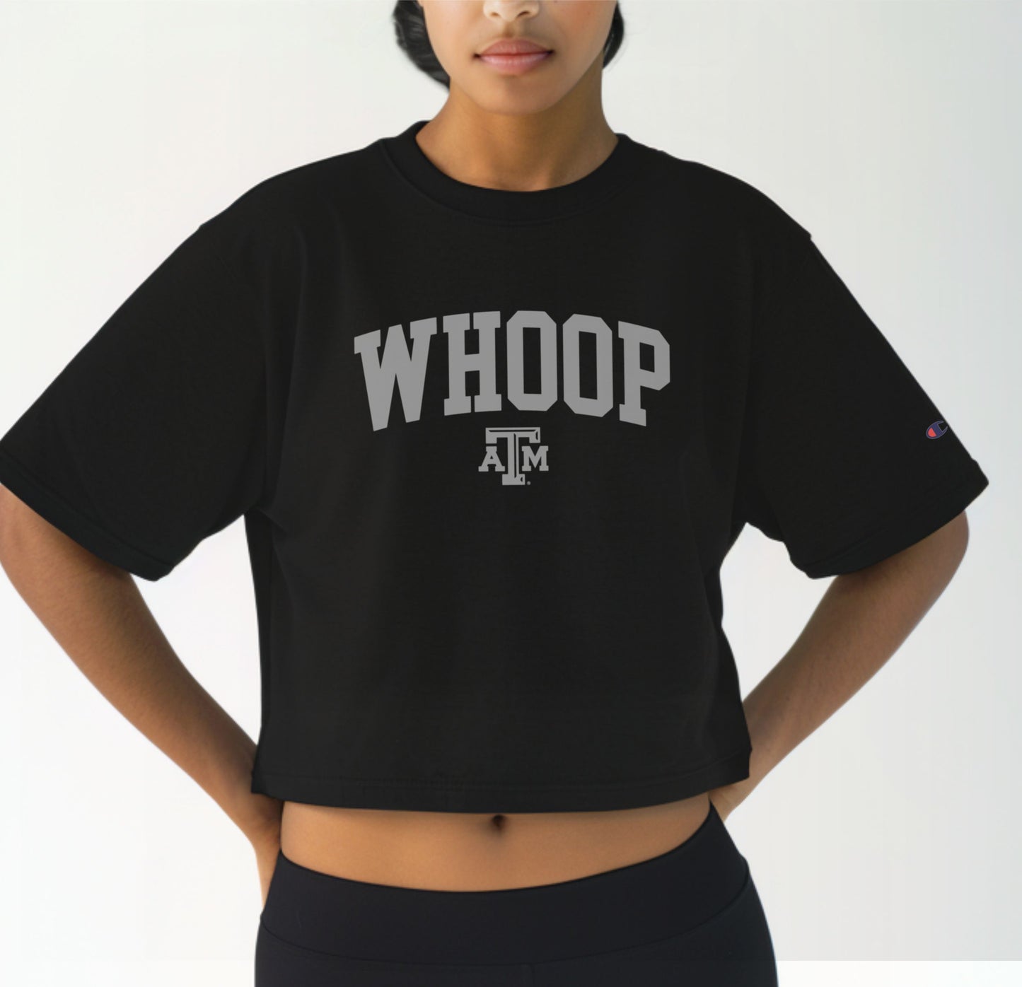 A model wears the Black Adult Womens Texas A&M Whoop Collegiate Crop Top.  The ﻿Texas A&M Whoop Collegiate﻿ graphic is in bold White in a Varsity style.