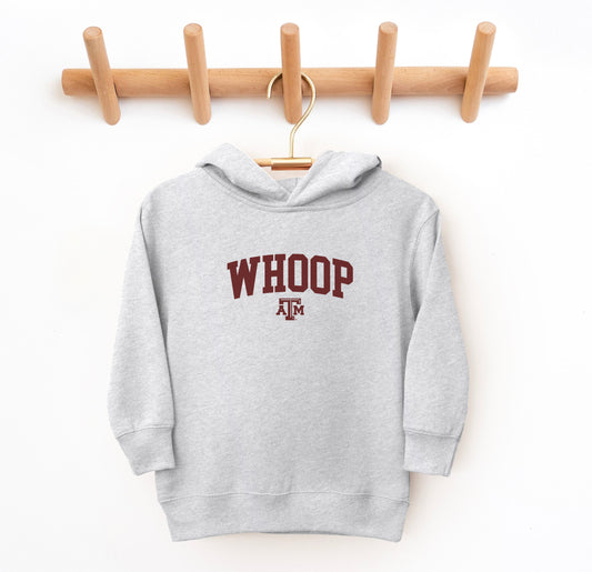 The Heather Grey Toddler Unisex Texas A&M Whoop Collegiate Hooded Sweatshirt lays flat on a white background. The ﻿Texas A&M Whoop Collegiate﻿ graphic is in bold Maroon in a Varsity style.