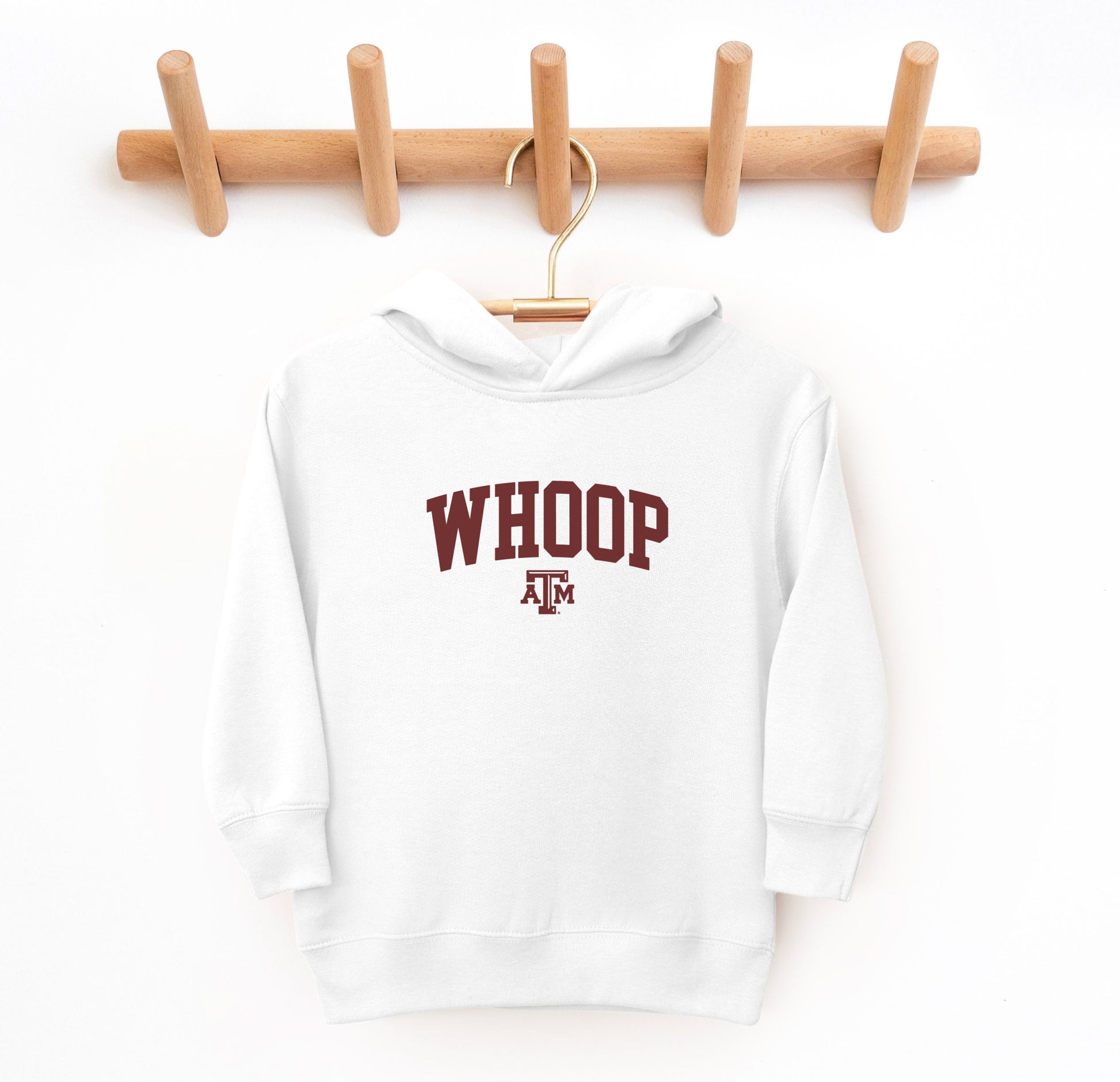 The White Toddler Unisex Texas A&M Whoop Collegiate Hooded Sweatshirt lays flat on a white background. The ﻿Texas A&M Whoop Collegiate﻿ graphic is in bold Maroon in a Varsity style.