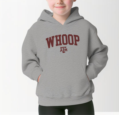 A model wears the Sport Grey Youth Unisex Texas A&M Whoop Collegiate Hooded Sweatshirt.  The ﻿Texas A&M Whoop Collegiate﻿ graphic is in bold Maroon in a Varsity style.