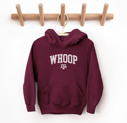 The Maroon Youth Unisex Texas A&M Whoop Collegiate Hooded Sweatshirt lays flat on a white background. The ﻿Texas A&M Whoop Collegiate﻿ graphic is in bold White in a Varsity style.