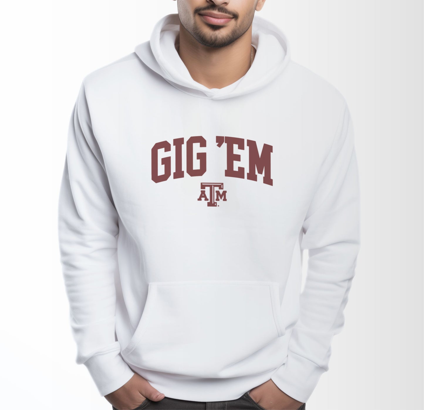 A model wears the White Adult Unisex Texas A&M Gig 'Em Collegiate Hooded Sweatshirt.  The ﻿Texas A&M Gig 'Em Collegiate﻿ graphic is in bold Maroon in a Collegiate style.