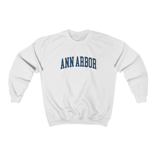 The White Adult Unisex Ann Arbor Michigan Varsity Crewneck Sweatshirt lays flat on a white background. The Ann Arbor Michigan Varsity graphic is in bold Navy in a Collegiate style.