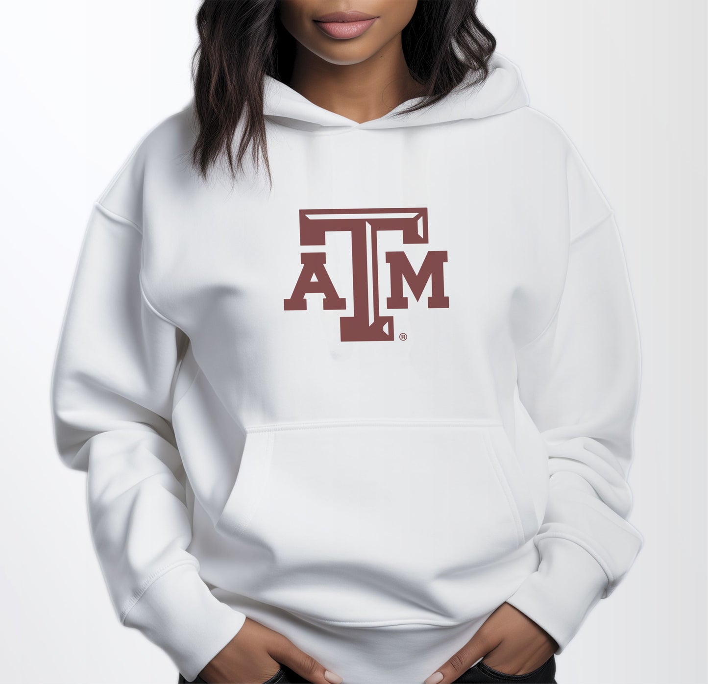 A model wears the White Adult Unisex Texas A&M Logo Hooded Sweatshirt.  The ﻿Texas A&M Logo﻿ graphic is in bold Maroon in a Varsity style.