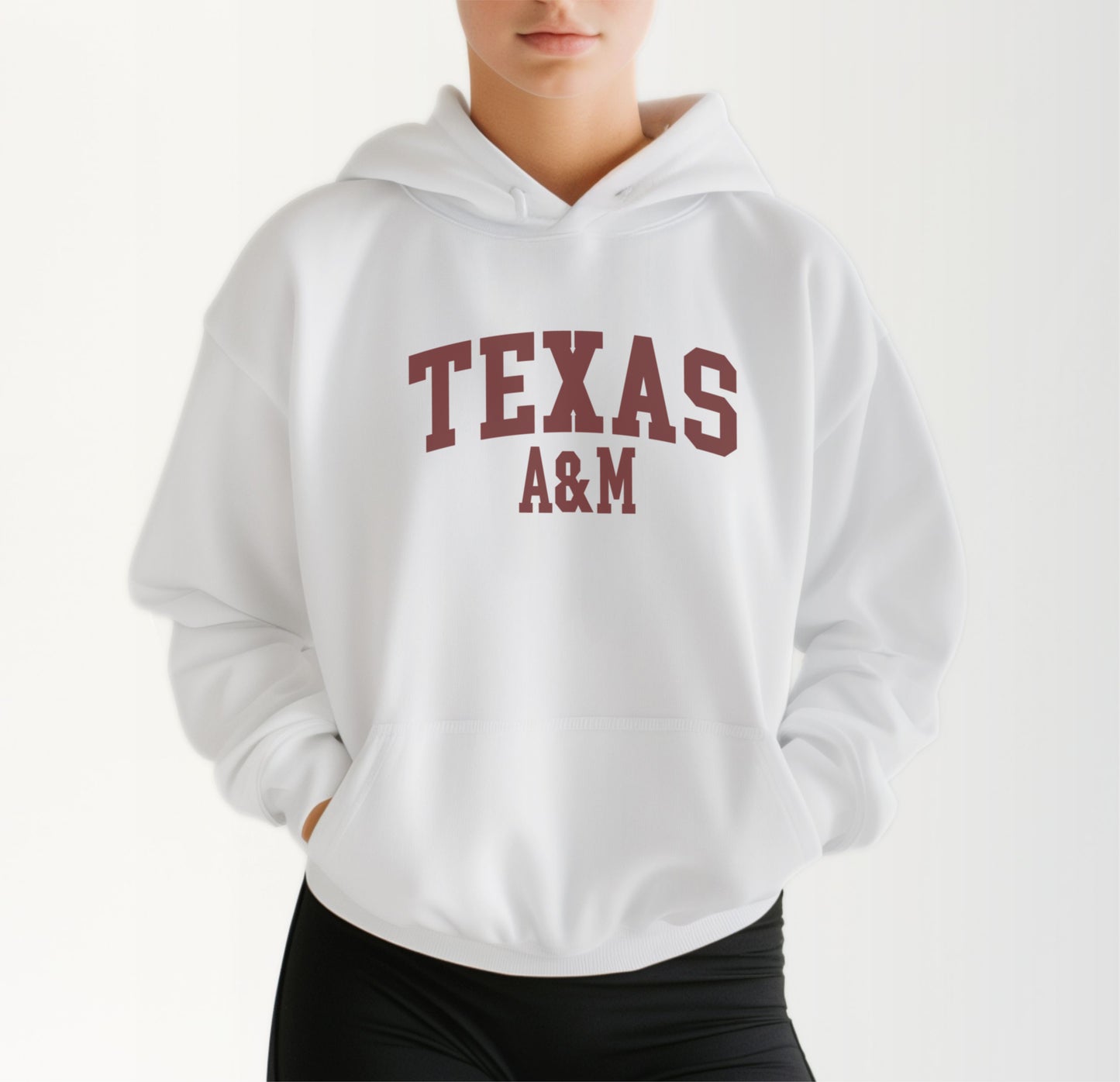 A model wears the White Adult Unisex Texas A&M Varsity Hooded Sweatshirt.  The ﻿Texas A&M Varsity﻿ graphic is in bold Maroon in a Collegiate style.