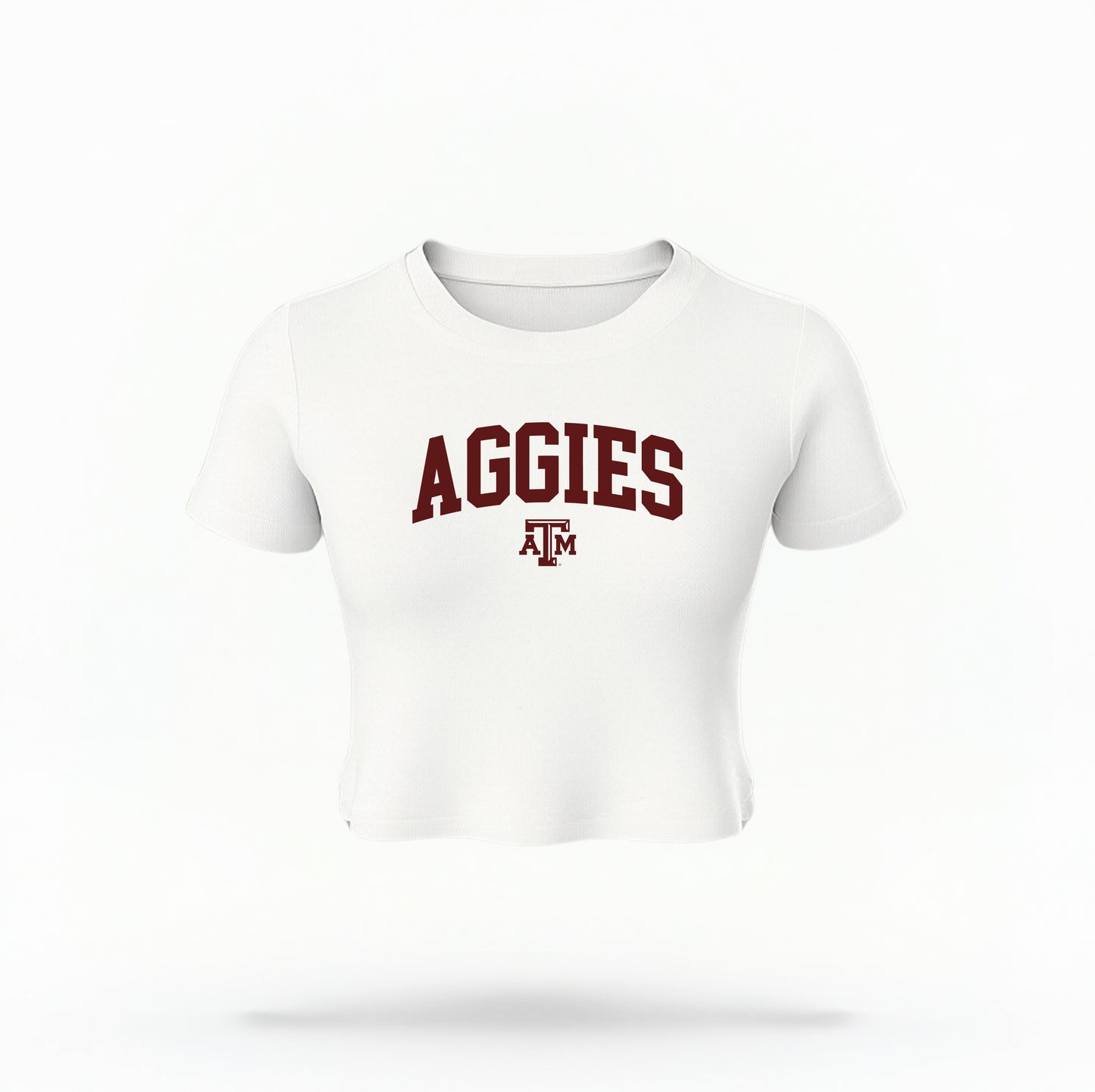 The White Texas A&M Aggies Collegiate Crop Top lays flat on a white background. The ﻿Texas A&M Aggies Collegiate﻿ graphic is in bold Maroon in a Varsity style.