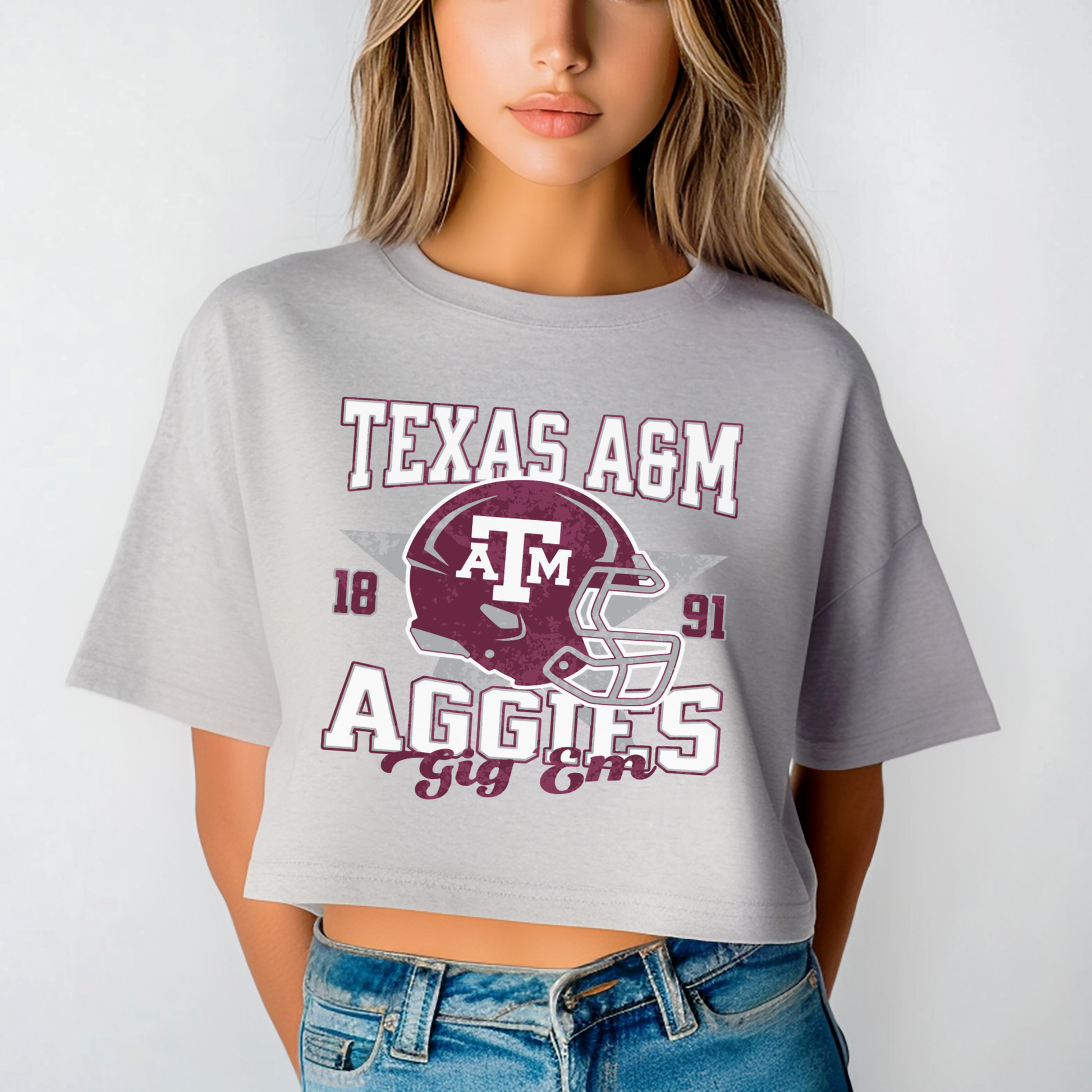 A model wears the Oxford Grey Texas A&M Aggies Football Crop Top. The ﻿Texas A&M Aggies Football﻿ graphic is in bold Multicolor in a Varsity style.