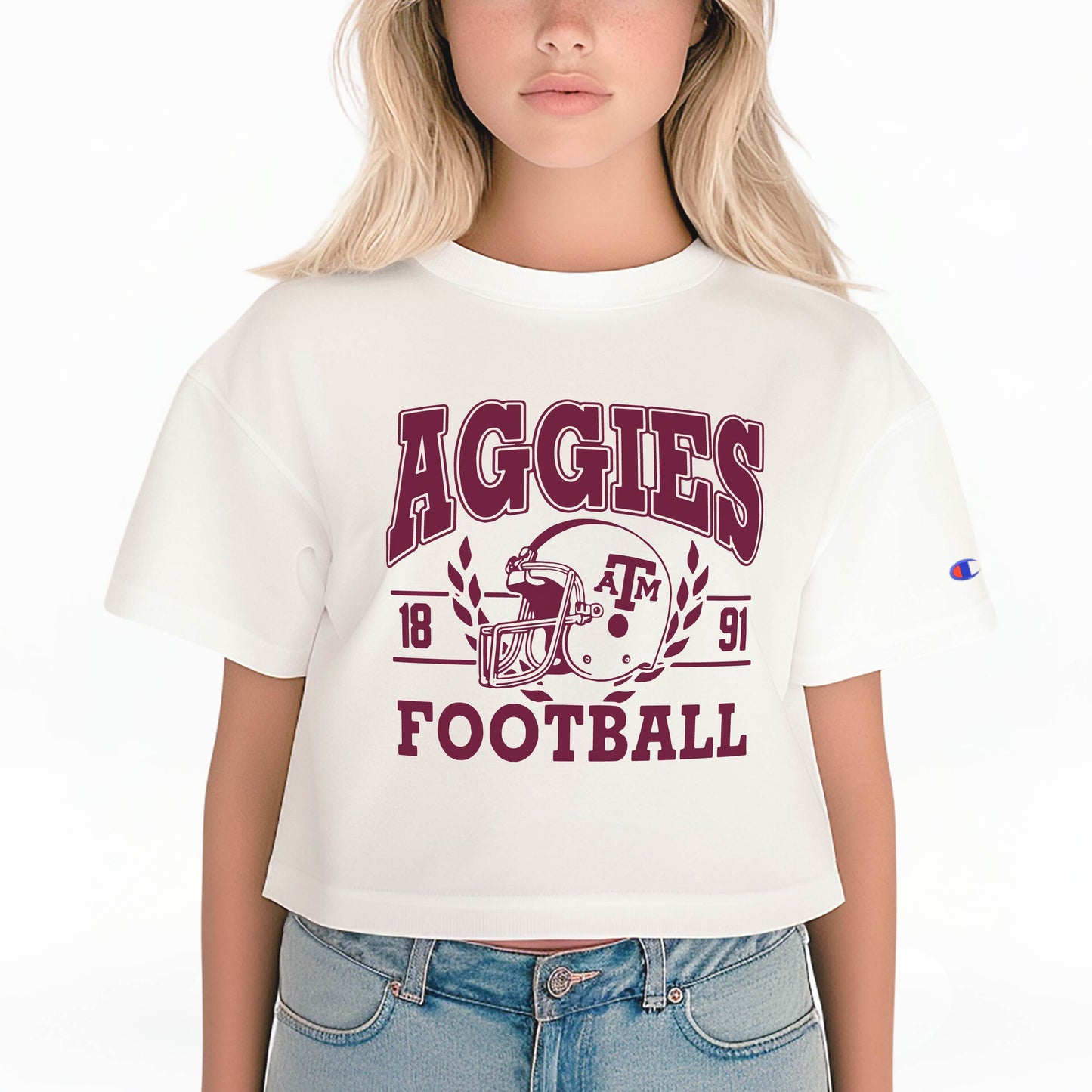 A model wears the White Texas A&M Aggie Football Crop Top.  The ﻿Texas A&M Aggie Football﻿ graphic is in bold Maroon.