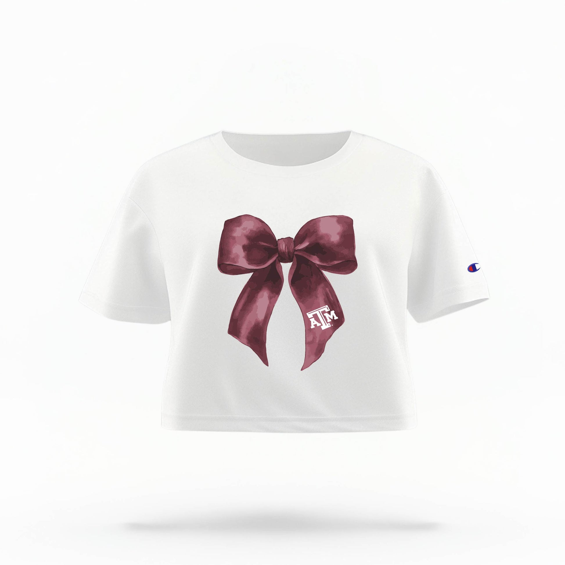 The White Texas A&M Bow Crop Top is shown on a ghost mannequin with a white background. The ﻿Texas A&M Bow﻿ graphic is in bold Maroon in a coquette style.