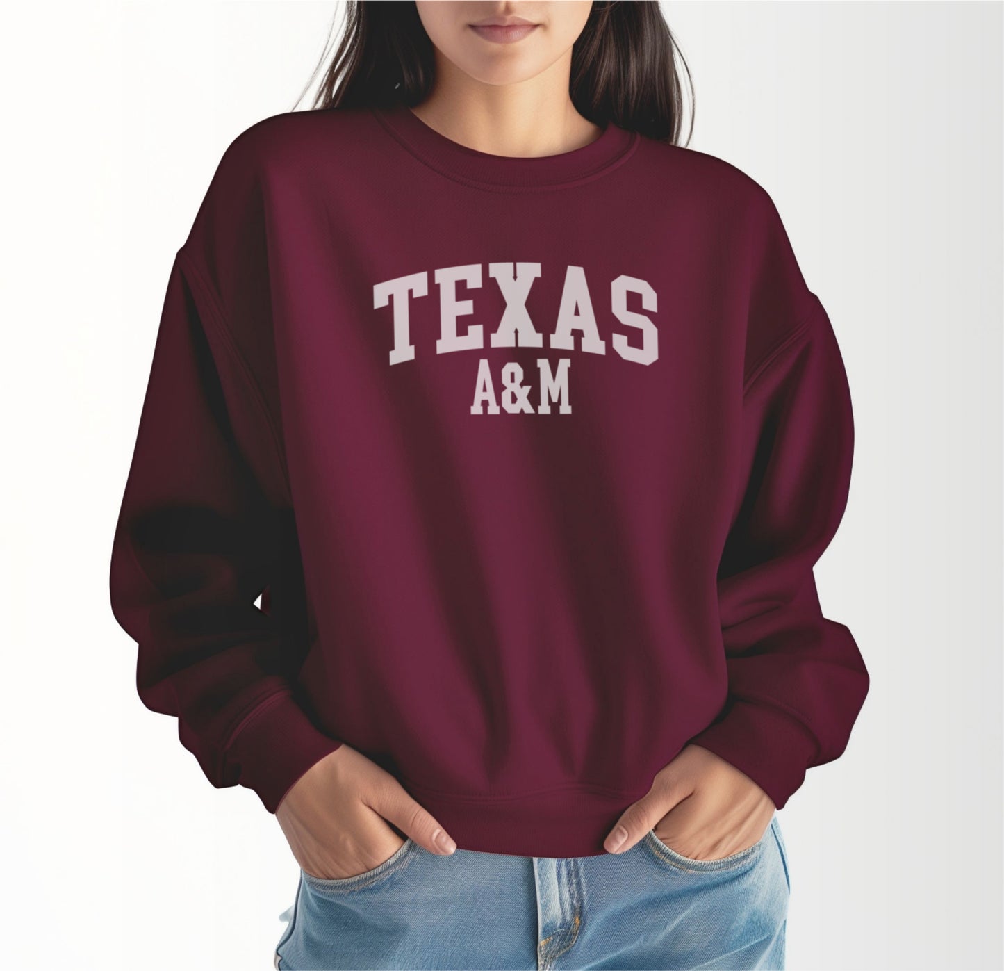 A model wears the Maroon Adult Unisex Texas A&M Varsity Crewneck Sweatshirt.  The ﻿Texas A&M Varsity﻿ graphic is in bold White in a Collegiate style.