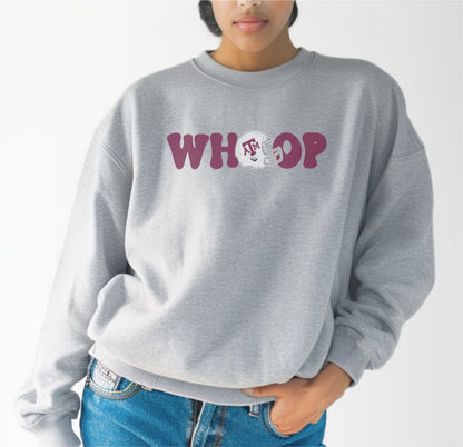 A model wears the Sport Grey Adult Unisex Texas A&M Retro Whoop Crewneck Sweatshirt.  The ﻿Texas A&M Retro Whoop﻿ graphic is in bold Maroon in a Vintage style.