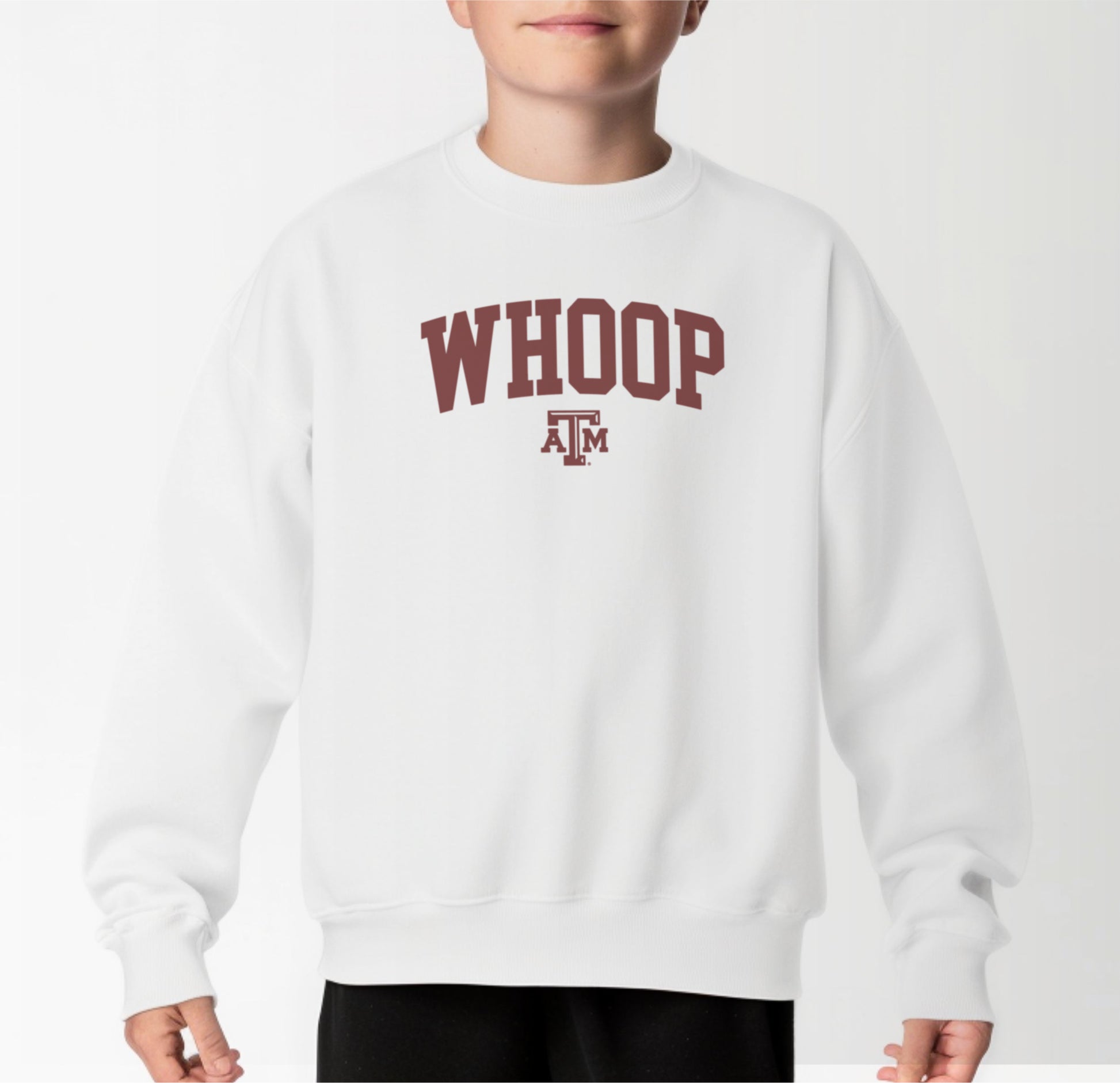 A model wears the White Youth Unisex Texas A&M Whoop Collegiate Crewneck Sweatshirt.  The ﻿Texas A&M Whoop Collegiate﻿ graphic is in bold Maroon in a Varsity style.