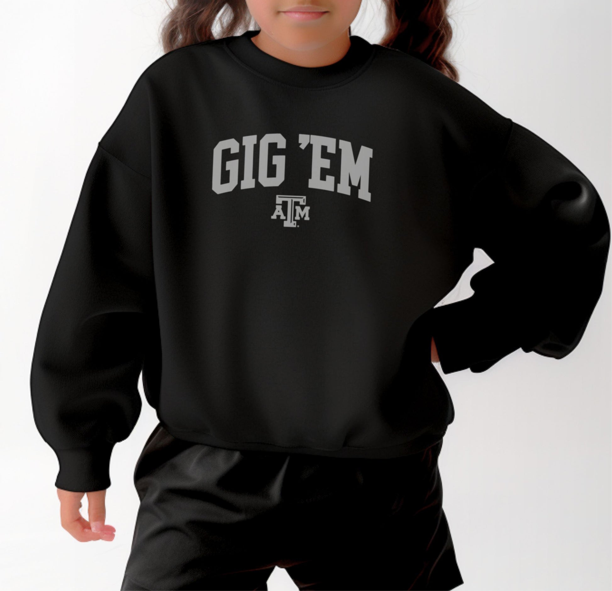 A model wears the Black Youth Unisex Texas A&M Gig 'Em Collegiate Crewneck Sweatshirt.  The ﻿Texas A&M Gig 'Em Collegiate﻿ graphic is in bold White in a Collegiate style.