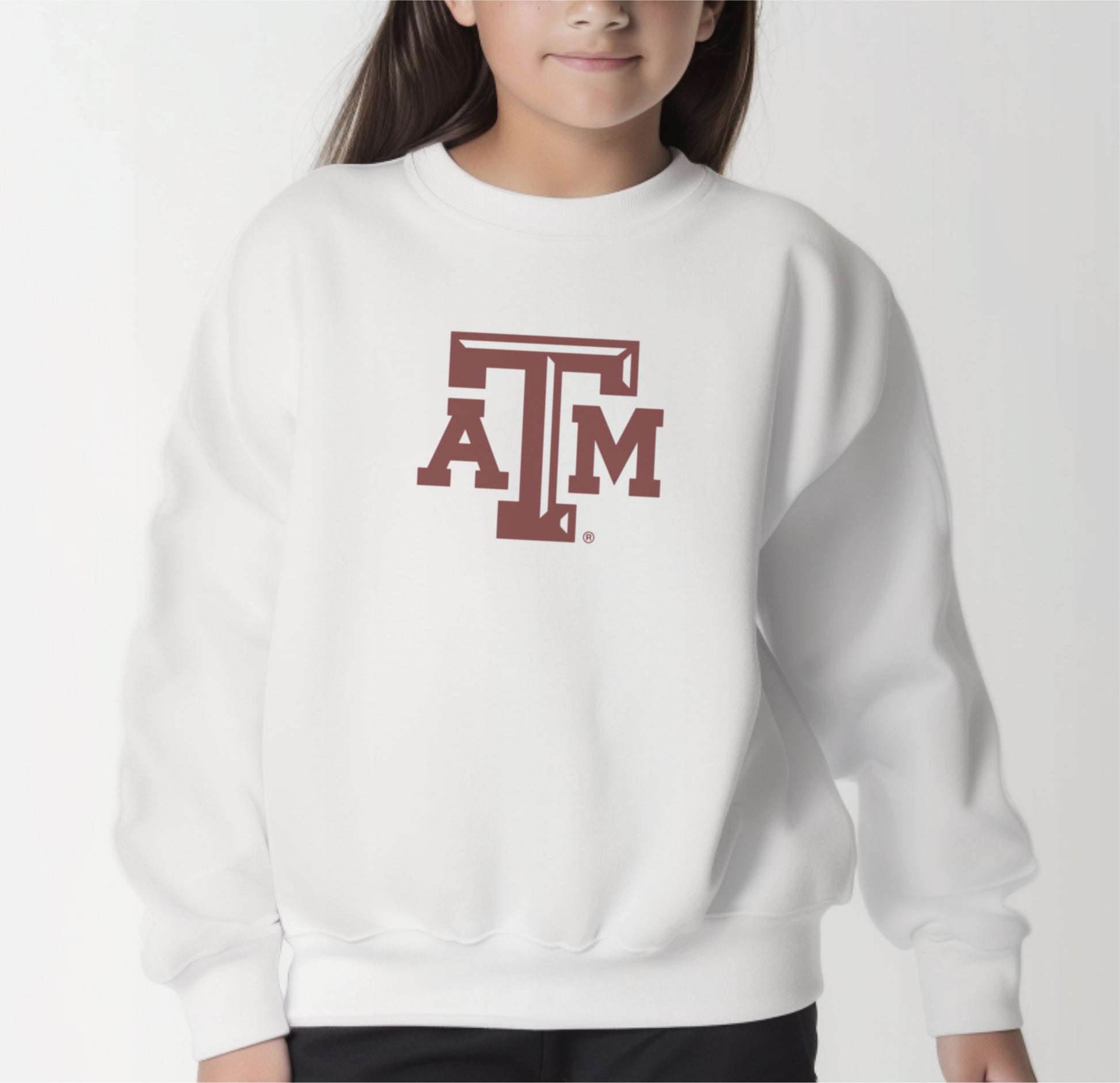 A model wears the White Youth Unisex Texas A&M Logo Crewneck Sweatshirt.  The ﻿Texas A&M Logo﻿ graphic is in bold Maroon in a Varsity style.