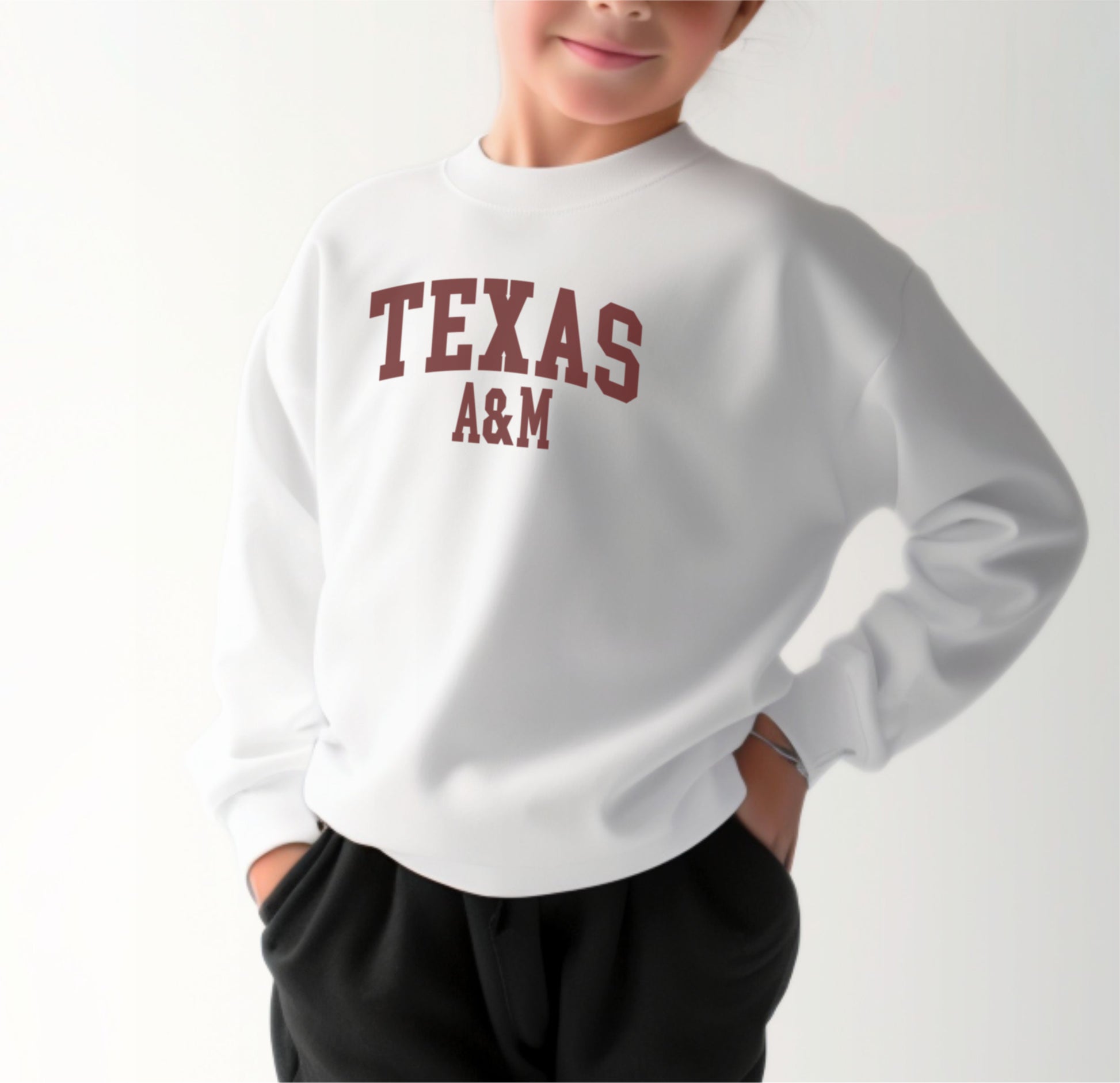 A model wears the White Youth Unisex Texas A&M Varsity Crewneck Sweatshirt.  The ﻿Texas A&M Varsity﻿ graphic is in bold Maroon in a Collegiate style.