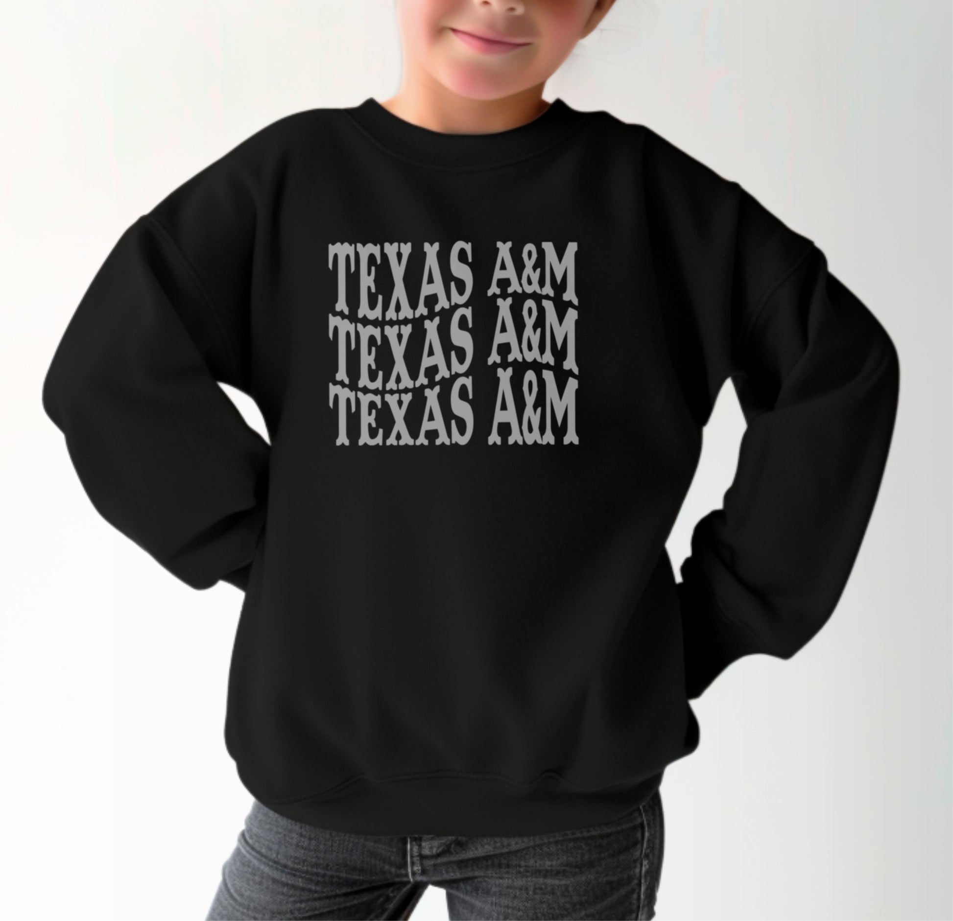 A model wears the Black Youth Unisex Texas A&M Western Crewneck Sweatshirt.  The ﻿Texas A&M Western﻿ graphic is in bold White in a Western style.