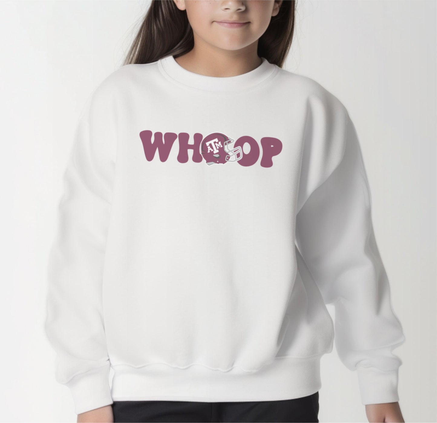 A model wears the White Youth Unisex Texas A&M Retro Whoop Crewneck Sweatshirt.  The ﻿Texas A&M Retro Whoop﻿ graphic is in bold Maroon in a Vintage style.