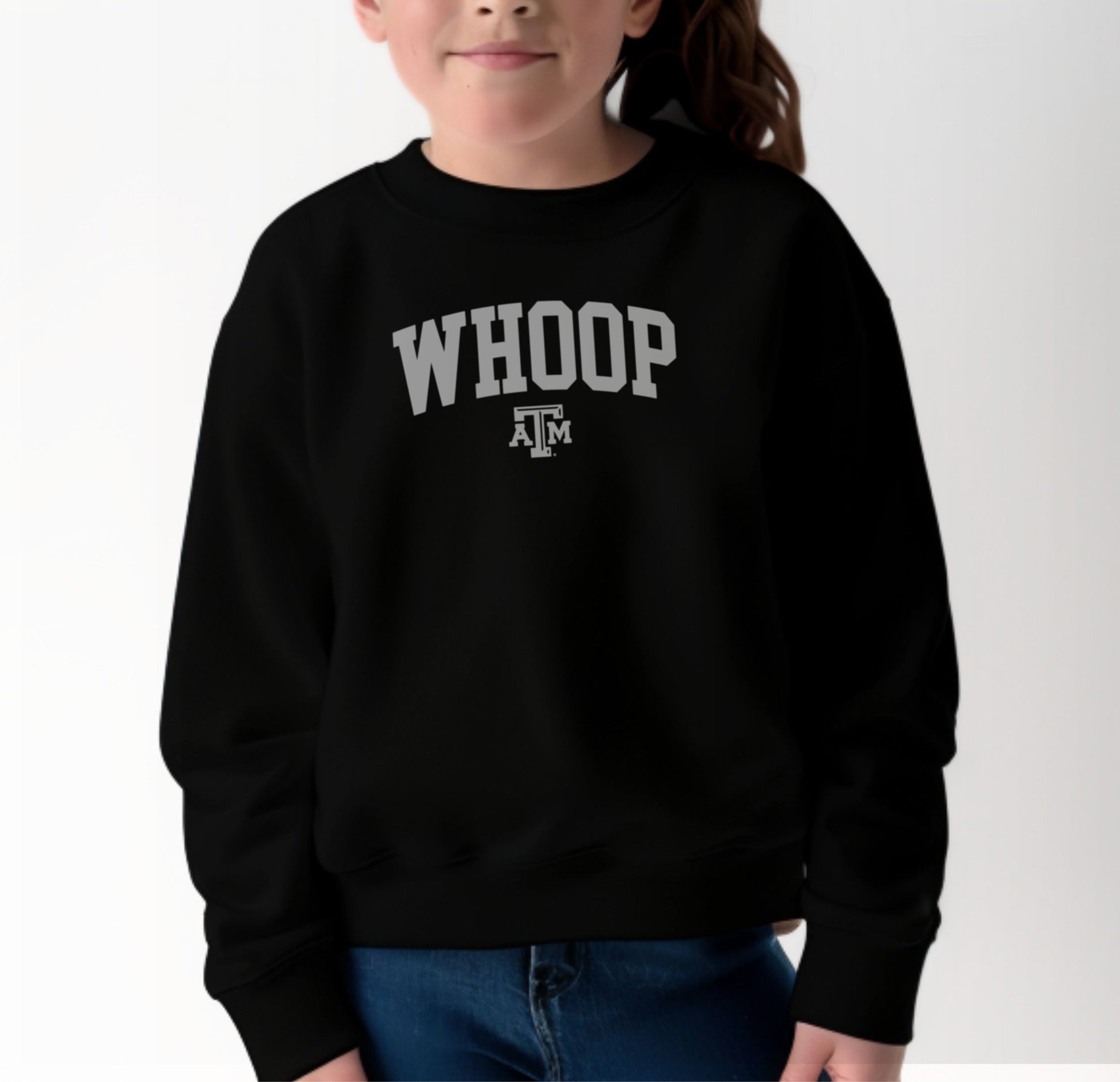 A model wears the Black Youth Unisex Texas A&M Whoop Collegiate Crewneck Sweatshirt.  The ﻿Texas A&M Whoop Collegiate﻿ graphic is in bold White in a Varsity style.