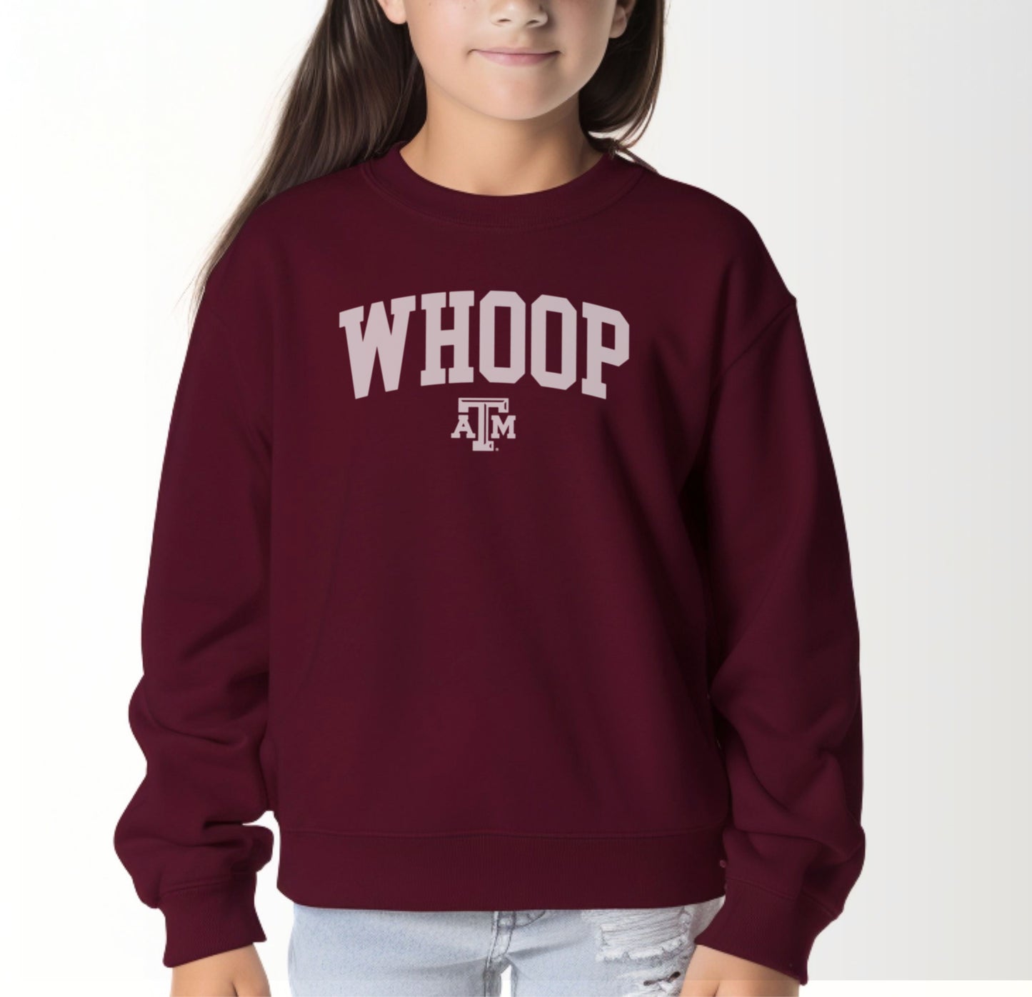 A model wears the Maroon Youth Unisex Texas A&M Whoop Collegiate Crewneck Sweatshirt.  The ﻿Texas A&M Whoop Collegiate﻿ graphic is in bold White in a Varsity style.