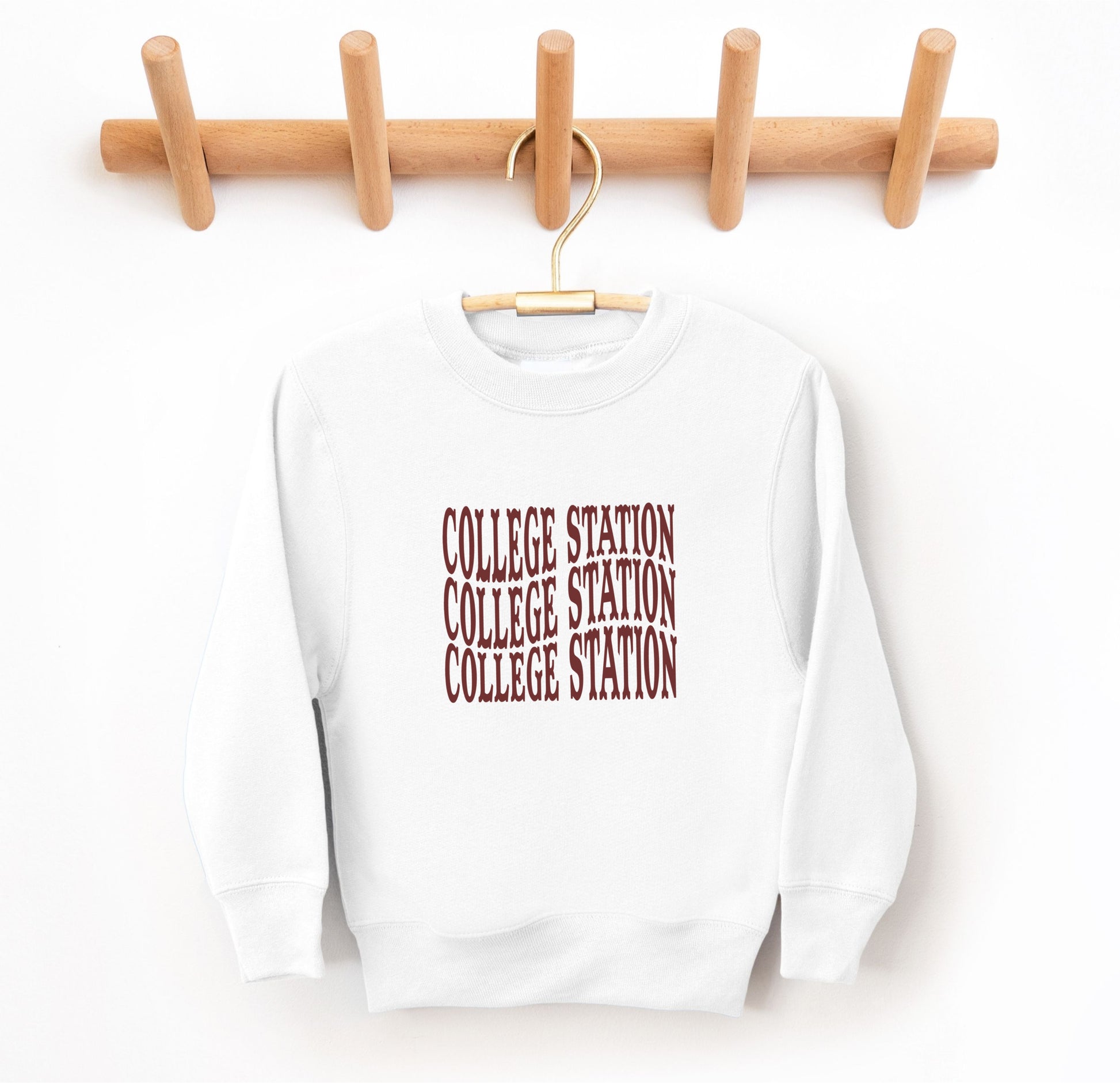 The White Youth Unisex College Station Western Crewneck Sweatshirt lays flat on a white background. The ﻿College Station Western﻿ graphic is in bold Maroon in a Western style.