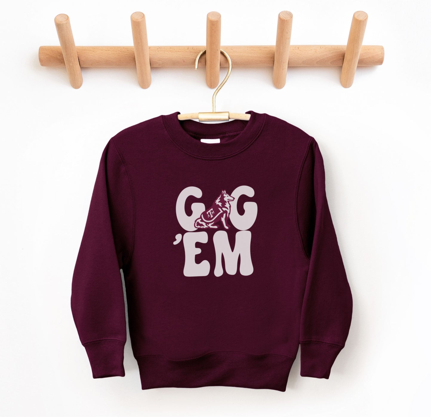 The Maroon Youth Unisex Texas A&M Gig 'Em Retro Reveille Crewneck Sweatshirt lays flat on a white background. The ﻿Texas A&M Gig 'Em Retro Reveille﻿ graphic is in bold White in a Groovy Vintage style.