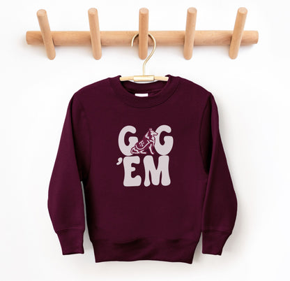 The Maroon Youth Unisex Texas A&M Gig 'Em Retro Reveille Crewneck Sweatshirt lays flat on a white background. The ﻿Texas A&M Gig 'Em Retro Reveille﻿ graphic is in bold White in a Groovy Vintage style.