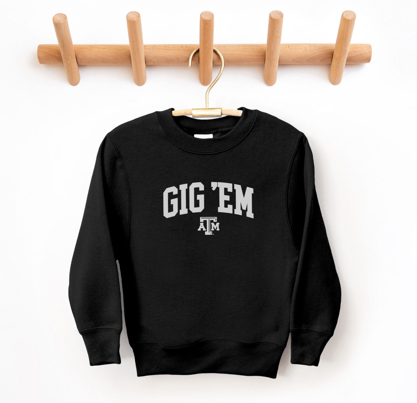 The Black Youth Unisex Texas A&M Gig 'Em Collegiate Crewneck Sweatshirt lays flat on a white background. The ﻿Texas A&M Gig 'Em Collegiate﻿ graphic is in bold White in a Collegiate style.