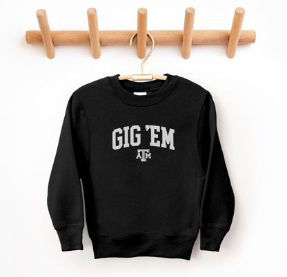 The Black Youth Unisex Texas A&M Gig 'Em Collegiate Crewneck Sweatshirt lays flat on a white background. The ﻿Texas A&M Gig 'Em Collegiate﻿ graphic is in bold White in a Collegiate style.