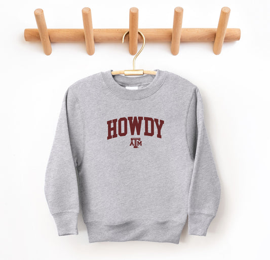 The Sport Grey Youth Unisex Texas A&M Howdy Varsity Crewneck Sweatshirt lays flat on a white background. The ﻿Texas A&M Howdy Varsity﻿ graphic is in bold Maroon in a Collegiate style.