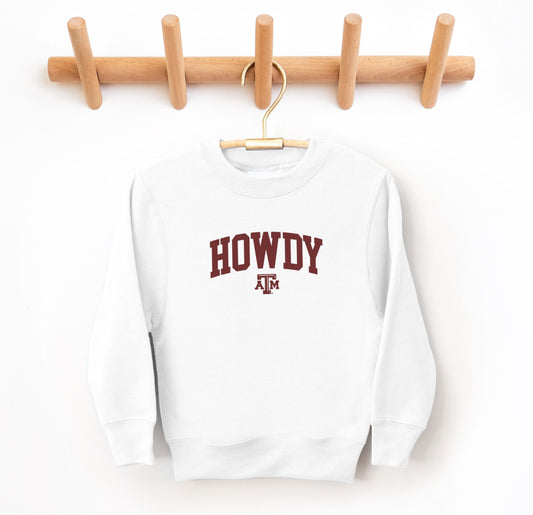 The White Youth Unisex Texas A&M Howdy Varsity Crewneck Sweatshirt lays flat on a white background. The ﻿Texas A&M Howdy Varsity﻿ graphic is in bold Maroon in a Collegiate style.