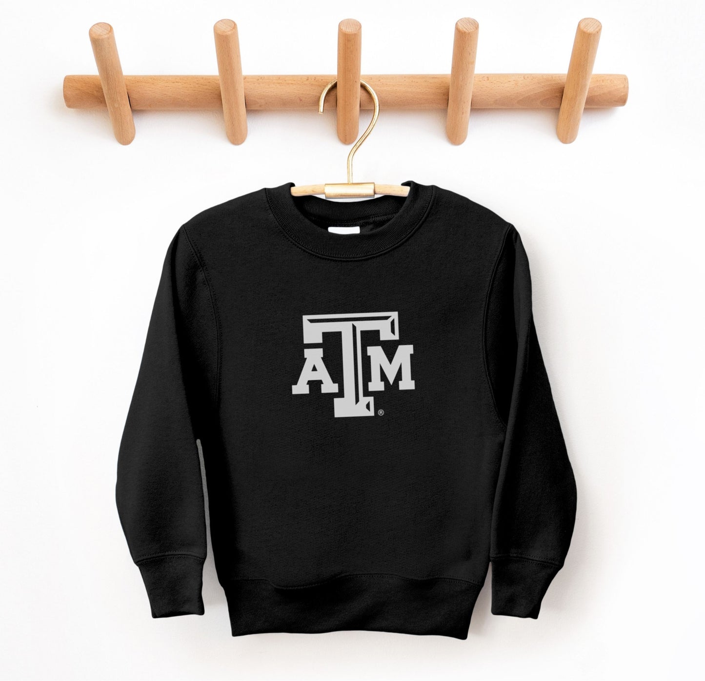 The Black Youth Unisex Texas A&M Logo Crewneck Sweatshirt lays flat on a white background. The ﻿Texas A&M Logo﻿ graphic is in bold White in a Varsity style.