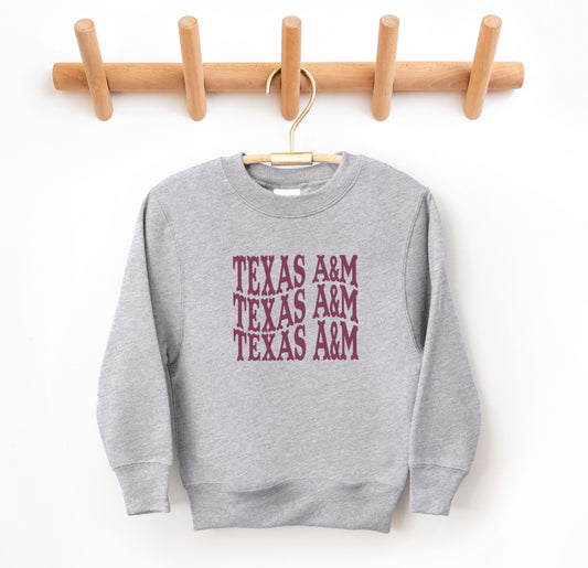 The Sport Grey Youth Unisex Texas A&M Western Crewneck Sweatshirt lays flat on a white background. The ﻿Texas A&M Western﻿ graphic is in bold Maroon in a Western style.