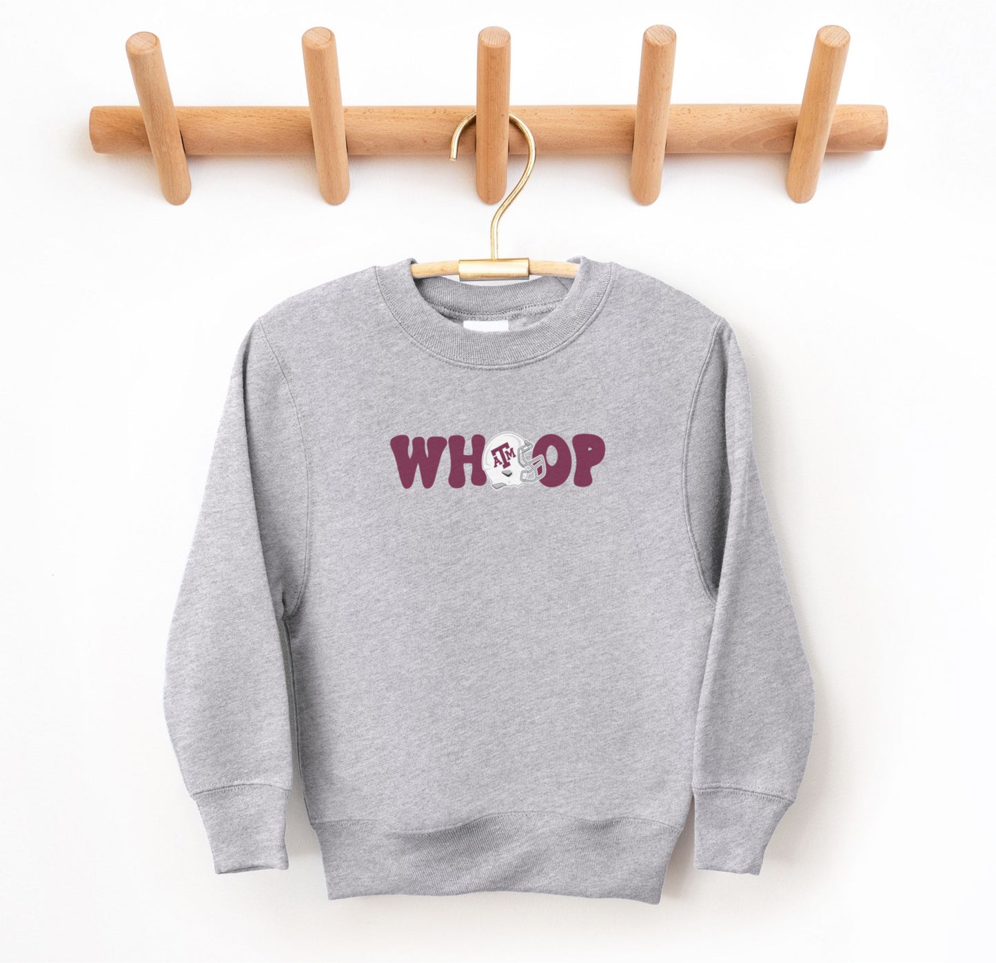 The Sport Grey Youth Unisex Texas A&M Retro Whoop Crewneck Sweatshirt lays flat on a white background. The ﻿Texas A&M Retro Whoop﻿ graphic is in bold Maroon in a Vintage style.