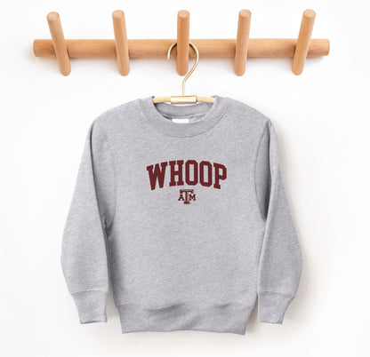 The Sport Grey Youth Unisex Texas A&M Whoop Collegiate Crewneck Sweatshirt lays flat on a white background. The ﻿Texas A&M Whoop Collegiate﻿ graphic is in bold Maroon in a Varsity style.