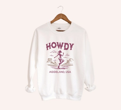 The White Howdy from Aggieland Western Crewneck Sweatshirt lays flat on a white background. The ﻿Howdy from Aggieland Western﻿ graphic is in bold Unisex in a Western style.