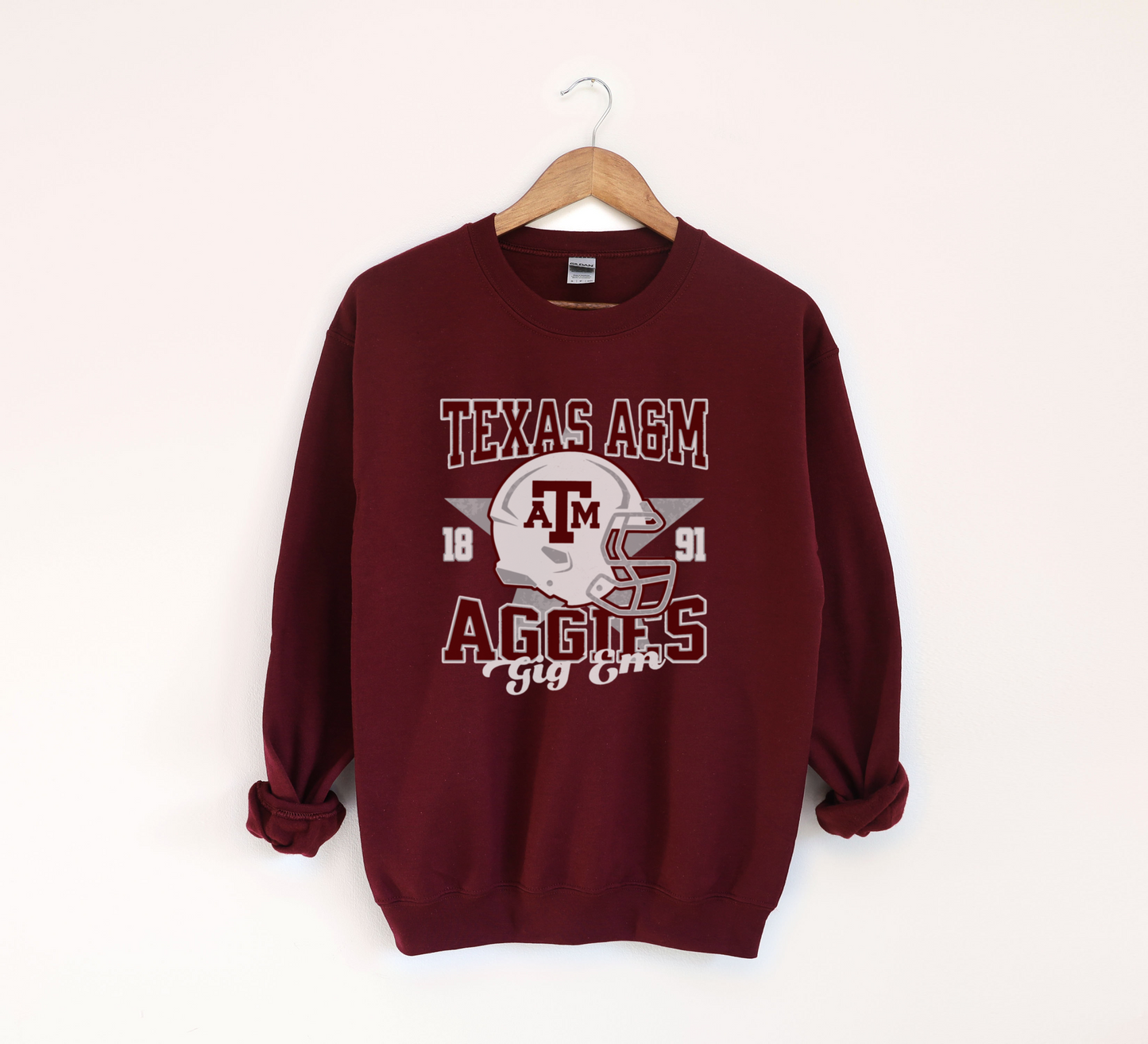 The Sport Grey Texas A&M Aggies Football Crewneck Sweatshirt lays flat on a white background. The ﻿Texas A&M Aggies Football﻿ graphic is in bold Unisex in a Varsity style.