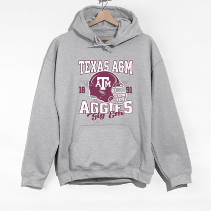 The Sport Grey Texas A&M Aggies Football Hoodie Sweatshirt lays flat on a white background. The ﻿Texas A&M Aggies Football﻿ graphic is in bold Unisex in a Varsity style.