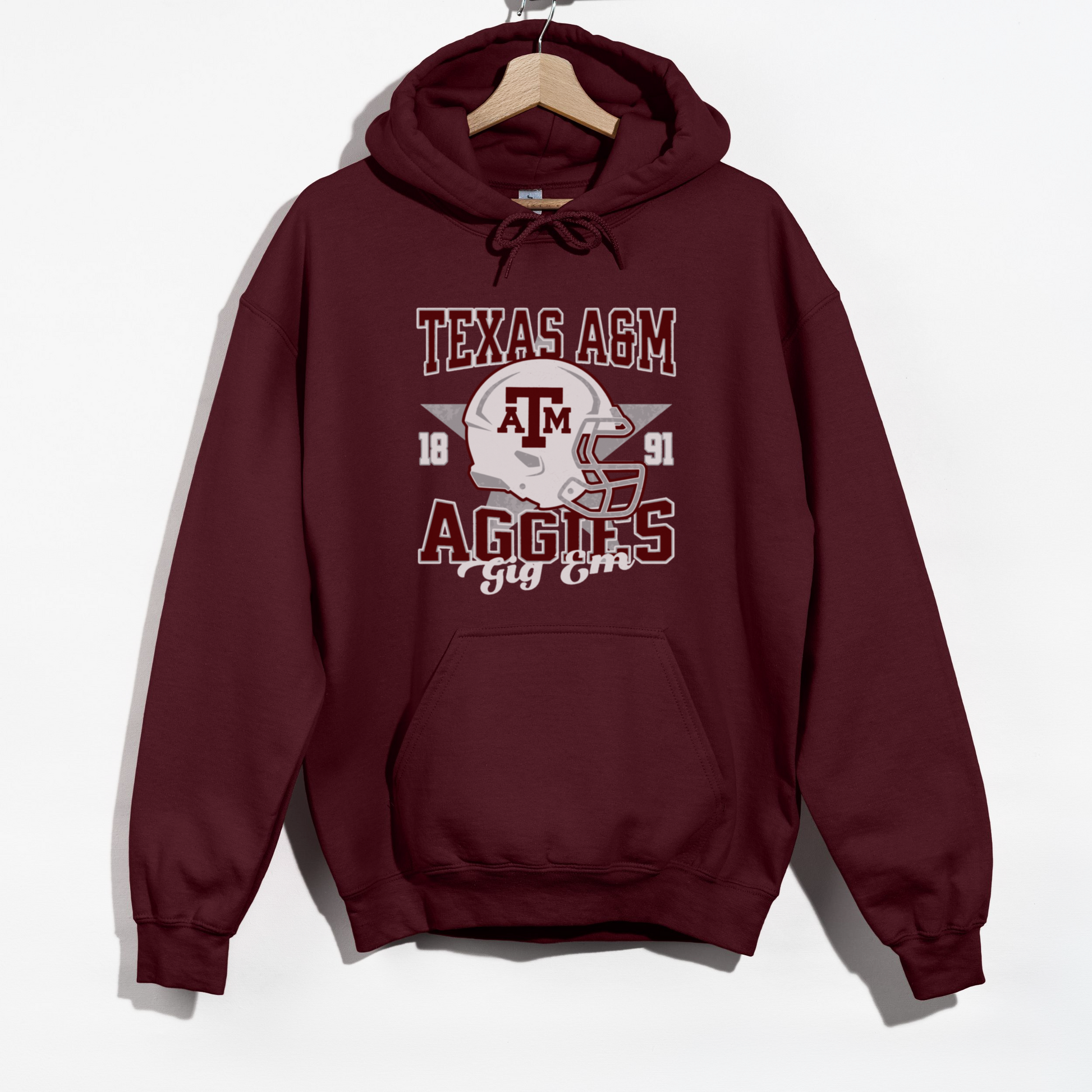 The Maroon Texas A&M Aggies Football Hoodie Sweatshirt lays flat on a white background. The ﻿Texas A&M Aggies Football﻿ graphic is in bold Unisex in a Varsity style.