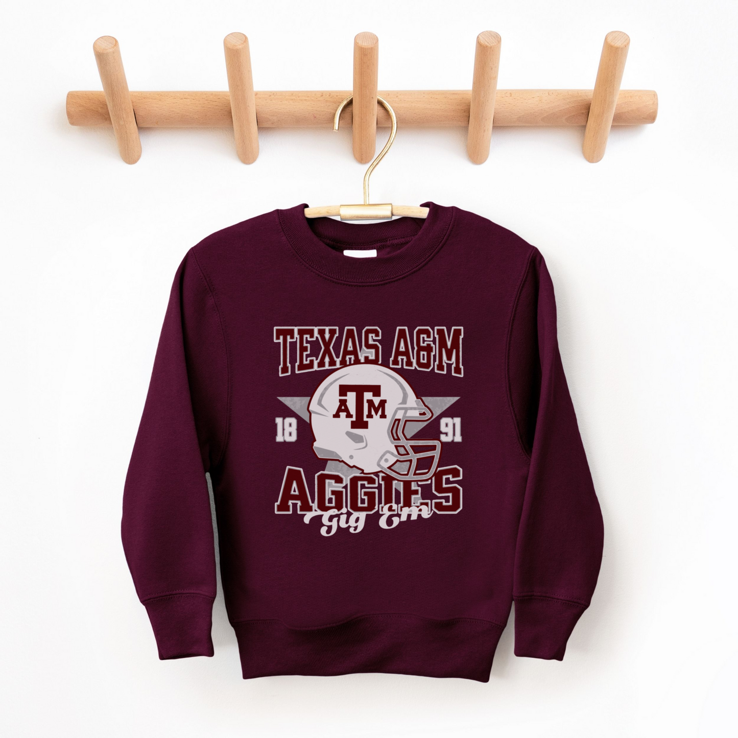 The Maroon Texas A&M Aggies Football Crewneck Sweatshirt lays flat on a white background. The ﻿Texas A&M Aggies Football﻿ graphic is in bold Multicolor in a Varsity style.