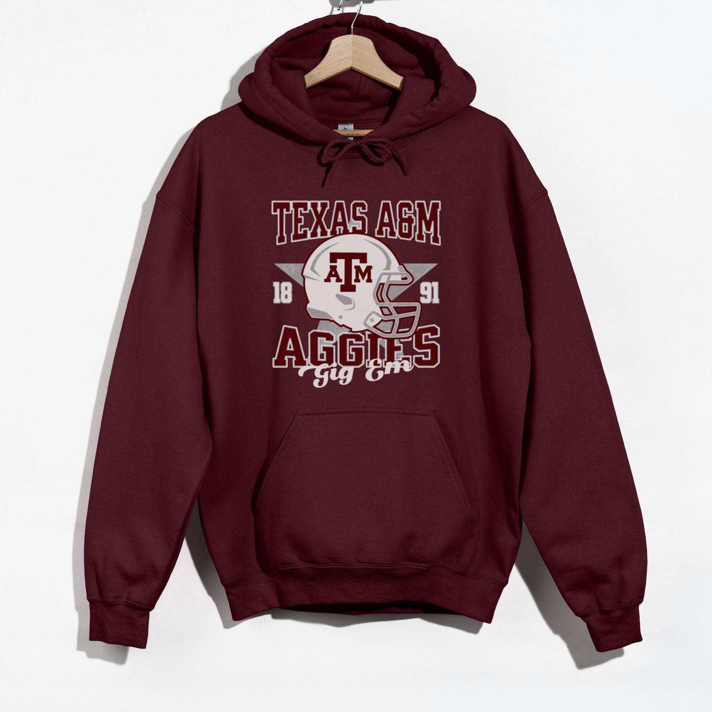 The Maroon Texas A&M Aggies Football Hoodie Sweatshirt lays flat on a white background. The ﻿Texas A&M Aggies Football﻿ graphic is in bold Unisex in a Varsity style.