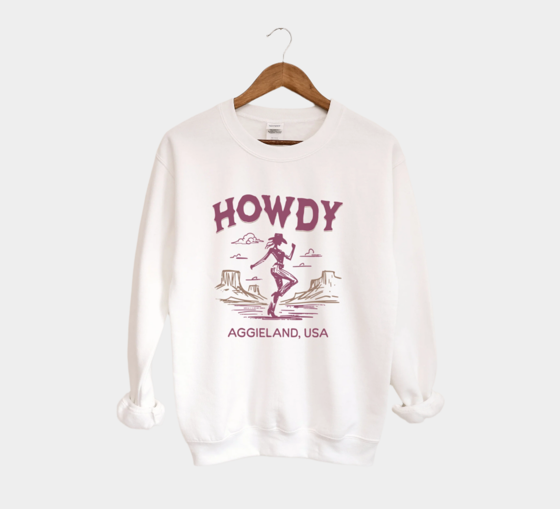 The White Howdy from Aggieland Western Crewneck Sweatshirt lays flat on a white background. The ﻿Howdy from Aggieland Western﻿ graphic is in bold Unisex in a Western style.