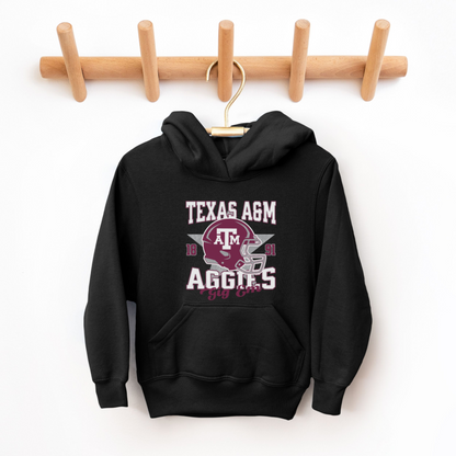 A model wears the Black Texas A&M Aggies Football Hooded Sweatshirt.  The ﻿Texas A&M Aggies Football﻿ graphic is in bold Multicolor in a Varsity style.