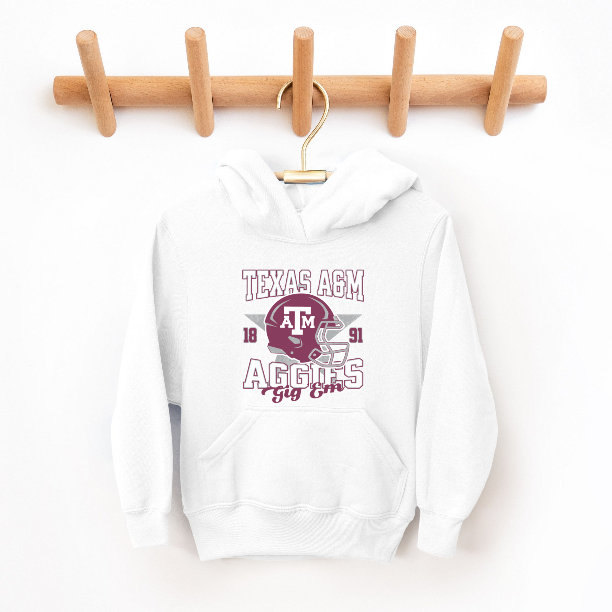 A model wears the White Texas A&M Aggies Football Hooded Sweatshirt.  The ﻿Texas A&M Aggies Football﻿ graphic is in bold Multicolor in a Varsity style.