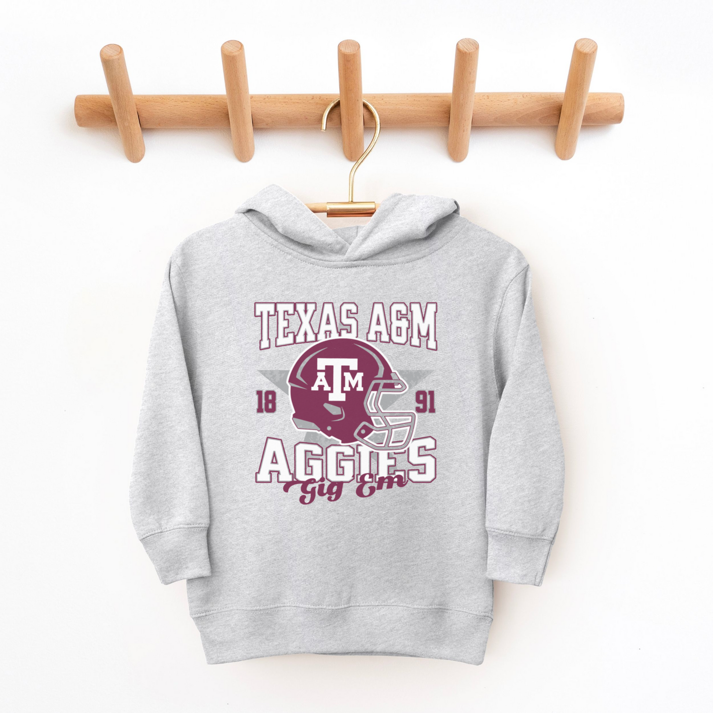 The Heather Grey Texas A&M Aggies Football Hooded Sweatshirt lays flat on a white background. The ﻿Texas A&M Aggies Football﻿ graphic is in bold Multicolor in a Varsity style.